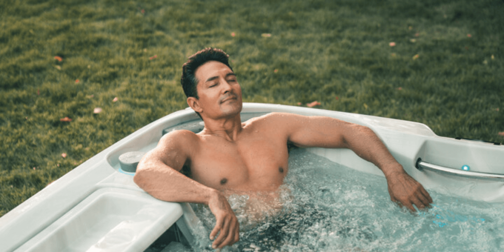an relaxing in a hot tub, using hydrotherapy jets for muscle recovery after a workout.